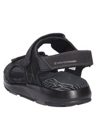 Sandalias negras con correas de velcro, plantilla acolchada y suela negra texturizada con rayas horizontales. Diseñadas para la comodidad y el soporte.