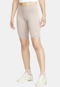 Ljusbeige Nike cykelshorts i stretchmaterial, med hög midja och diskret logotypdetalj på låret.