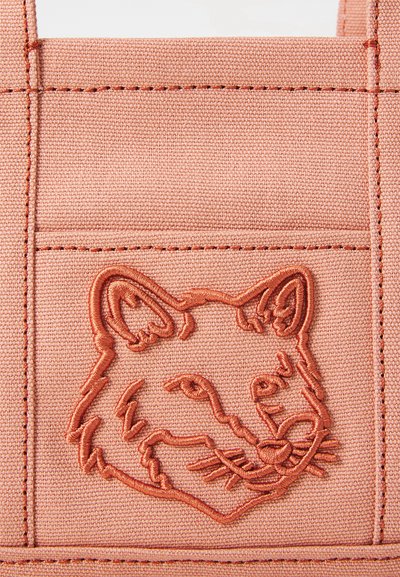 Bolsa de lona en suave melocotón con un diseño de zorro bordado texturizado. Presenta costuras reforzadas y un bolsillo estructurado.
