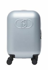 Valise rigide argentée avec quatre roues pivotantes noires et un logo ovale en relief au centre avant.