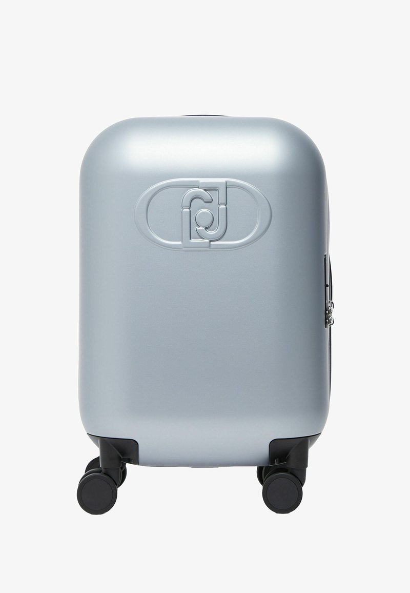 Valise rigide argentée avec quatre roues pivotantes noires et un logo ovale en relief au centre avant.