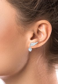 Silberne, flügelförmige Ohrringe mit einem klaren Edelstein-Anhänger, die ein schlankes Design mit filigranen Details betonen.