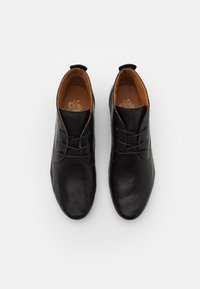 Pair of black leather lace-up shoes with tan interior lining, viewed from above on a white background.