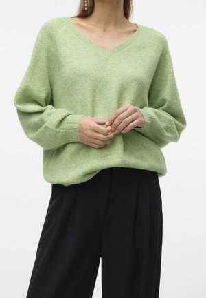Pull vert à col en V en tissu doux et texturé. Doté de manches amples et d'une coupe décontractée. Assorti à un pantalon noir sur mesure.