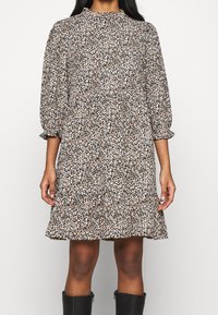 Blumengemustertes Kleid mit hochgeschlossenem Ausschnitt, Ballonärmeln, in Schwarz, Creme und Orangetönen, fließender Textur und einem Rüschensaum.