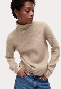 Beige geribbelde turtleneck trui met een relaxte pasvorm en lange mouwen, voorzien van een textuur breiwerk en geribbelde boorden en zoom. Draag over denim.