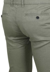 Olijfgroene broek van katoenmix, met een gladde textuur, achterzak met knoopsluiting en een getailleerde pasvorm.