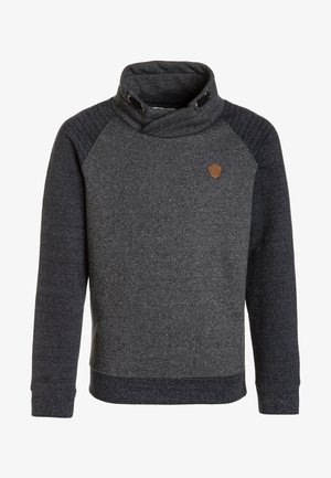 Ciemnoszara bluza z wysokim kołnierzem, prążkowaną teksturą na ramionach i małą, brązową naszywką z logo na piersi. Posiada długie rękawy i przylegający krój.