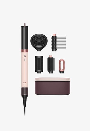 Il set di strumenti per acconciare i capelli include una spazzola riscaldata rose gold e nera, accessori per lo styling e una custodia coordinata. Diverse superfici testurizzate sono visibili.