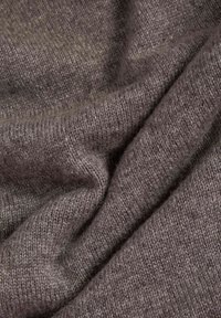 Grauer Strickstoff mit einer weichen Textur, der ein dezentes Farbverlaufsmuster und ein locker gewebtes Design aufweist, mit Falten und Drapierungen.