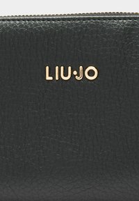 Portafoglio in pelle nera con finitura testurizzata, logo dorato "LIU·JO" e chiusura con zip lungo il bordo superiore.