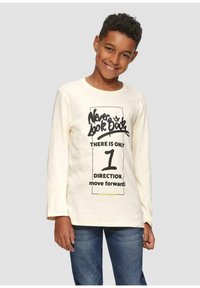 Cremfarbener Langarm-T-Shirt mit schwarzem Grafiktext: "Blicke niemals zurück" und "Es gibt nur eine Richtung. Vorwärts bewegen!" Kombiniert mit blauer Jeans.