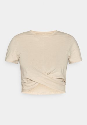 Beige kortärmad crop top med rund halsringning och knutdetalj framtill, tillverkad i lätt tyg.