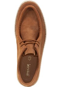 Braune Wildlederschuhe mit runder Spitze, Schnürdetails und einer strukturierten, hellen Sohle. Goldenes Logo-Detailing innen.