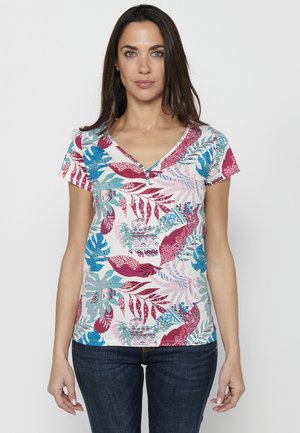 Chemise à col en V à manches courtes en tissu léger, ornée de motifs de feuilles tropicales multicolores, avec des accents bleus et rouges, et des boutons décoratifs au niveau du col.