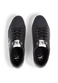 Baskets noires à lacets avec une tige synthétique lisse, une semelle en caoutchouc blanche et un détail de logo de marque sur le côté et la languette.