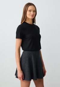 Schwarzes, geripptes Kurzarmoberteil kombiniert mit einem grauen, aus weichem Fleece gefertigten, ausgestellten Rock, der eine glatte Textur und ein einfaches Design aufweist.