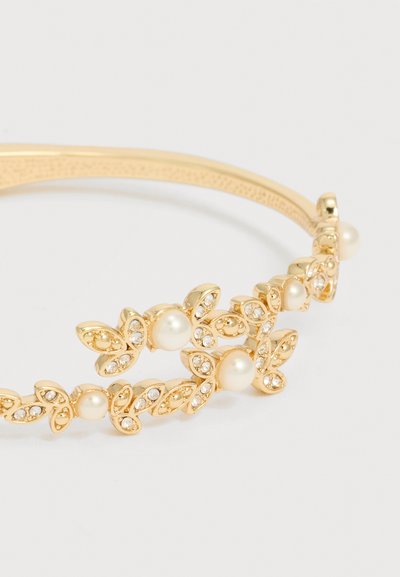 Χρυσό βραχιόλι με ρυθμίσεις σε σχήμα φύλλου, μικρές διαφανείς πέτρες και στρογγυλές λευκές πέρλες τακτοποιημένες κατά μήκος της λωρίδας.