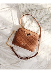 Braune Fake-Leder-Crossbody-Tasche mit einem gesteppten Muster, goldener Kette und Tragegurt sowie einem kontrastierenden Creme-Akzent. Reißverschlussverschluss oben.