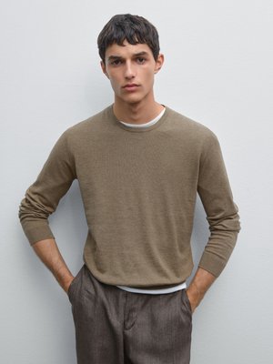 Brown knit sweater with a round neckline and long sleeves, paired with textured gray trousers. Smooth fabric with a fitted design.