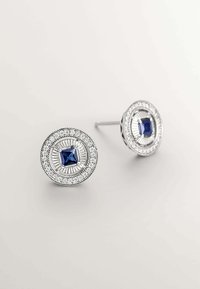 Pendientes de plata con un diseño de piedra azul cuadrada en el centro, rodeada por un marco circular con un detallado intrincado y acentos claros.