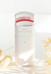 Stylpro-apparaat in witte plastic met een rode accent. Beschikt over een gebogen deksel en een kleine knop. Glad oppervlak en compacte rechthoekige vorm.