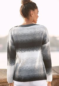 Schwarzer und weißer Strickpullover mit einem Farbverlaufmuster, langen Ärmeln, Rundhalsausschnitt und lockerer Passform. Glatte Textur mit gerippten Akzenten.
