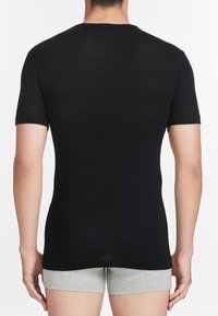T-shirt nera a maniche corte con un design aderente, realizzata in un materiale liscio, caratterizzata da un collo rotondo e uno stile minimalista.