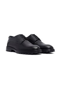 Zwarte leren schoenen met een textuurafwerking, met een ronde neus, vetersluiting en een stoere rubberen zool met gripgroeven.