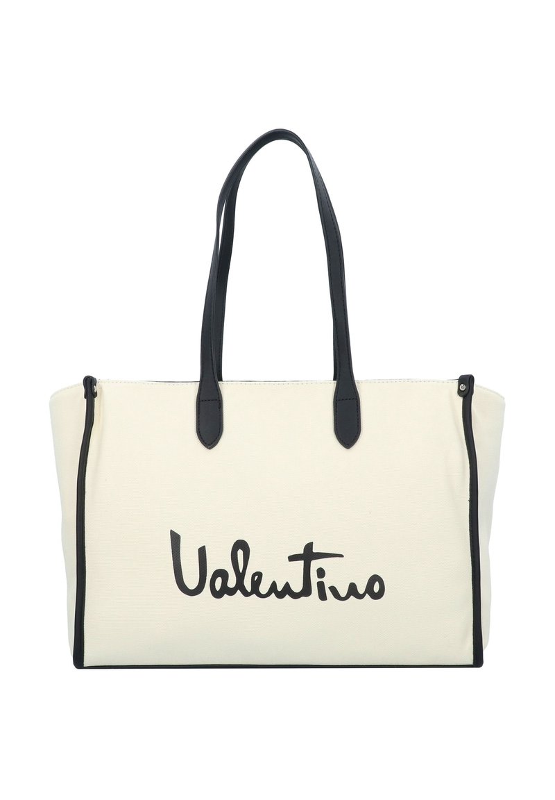 Canvas tote bag in off-white with black leather accents. Features long handles and a prominent black logo print. Zipper top closure.