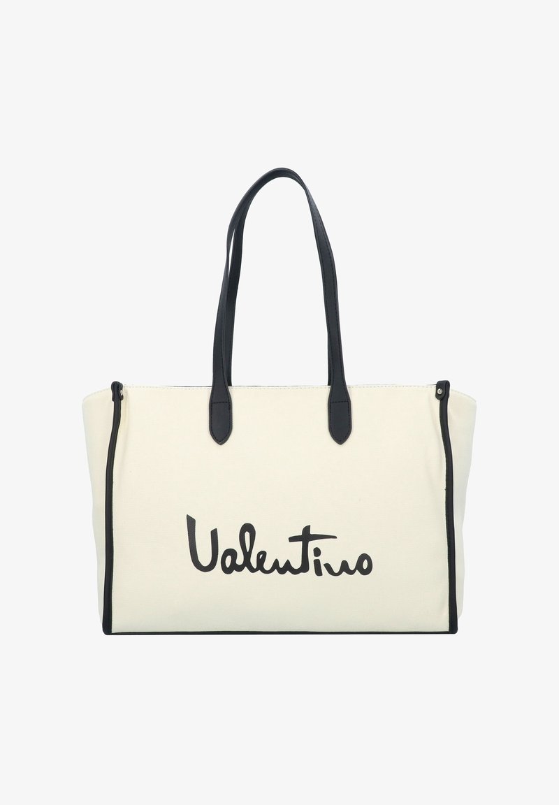 Canvas tote bag in off-white with black leather accents. Features long handles and a prominent black logo print. Zipper top closure.