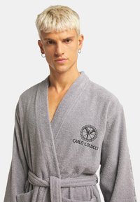 Grau terry Stoff Morgenmantel mit Wickeldesign, Taillenkordel und gestickten Logodetails auf der Brust, bietet eine weiche Textur und Komfort.