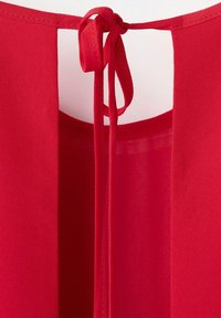 Decolteu al unei haine roșii cu o deschidere tip cheie, fixată printr-un șnur din același material legat într-un arc la spatele central.