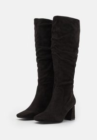 Schwarze Kunstwildleder-Stiefel in kniehoher Form mit einem lockeren Design, spitzem Zehenbereich und chunky Blockabsatz verfügen über einen seitlichen Reißverschluss und eine glatte Textur.