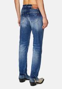 Blå denimjeans med en blekt finish och slitna detaljer, med midjeficka, raka ben och en läderetikett på baksidan.