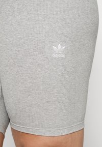 Grå rutiga shorts i en bomullsblandning med en liten vit Adidas-logotyp på vänster sida. Slät textur med en figurnära design.