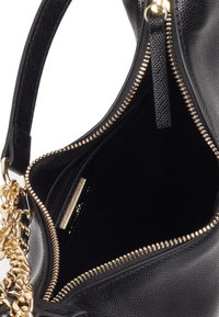 Czarna skórzana torebka z złotą zamkiem błyskawicznym, łańcuszkowymi detalami i gładkim wnętrzem. Widoczna kieszeń z zamkiem błyskawicznym w środku.