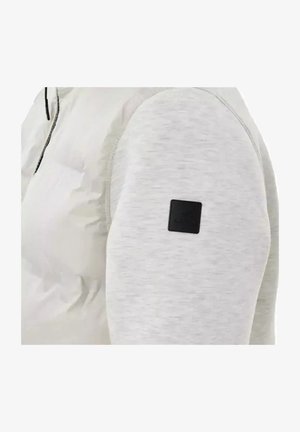 Giacca grigia chiara con fronte imbottito, maniche lisce e una toppa nera con il logo sul braccio sinistro per un tocco di dettaglio.