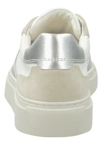 Weißer Sneaker mit beigen Wildlederakzenten und metallic-silberner Fersenlasche, von hinten gezeigt mit dicker weißer Sohle und texturiertem Fersenhalt.