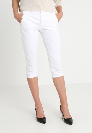 Pantalones capri blancos con bolsillos frontales y corte recto. La tela parece suave con un ligero brillo; combinados con zapatos de tacón negro.