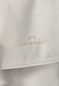 Ljust grått canvasmaterial har en subtil textur. Logotypen "DOUGHNUT" är präglad i guld, med minimalistiska bergaccenter.