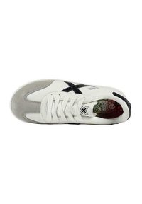 Sneaker bianca con accenti in suede grigio, logo nero e suola testurizzata. Presenta un design con lacci e una soletta colorata con motivo.