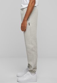 Lysegrå sweatpants lavet af blødt stof, med tapered ben, elastisk talje og sidelommer, parret med hvide sneaks.