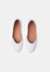 Bailarinas de piel blanca con punta redondeada, detalles cosidos a lo largo de la suela y un interior suave con acentos perforados.