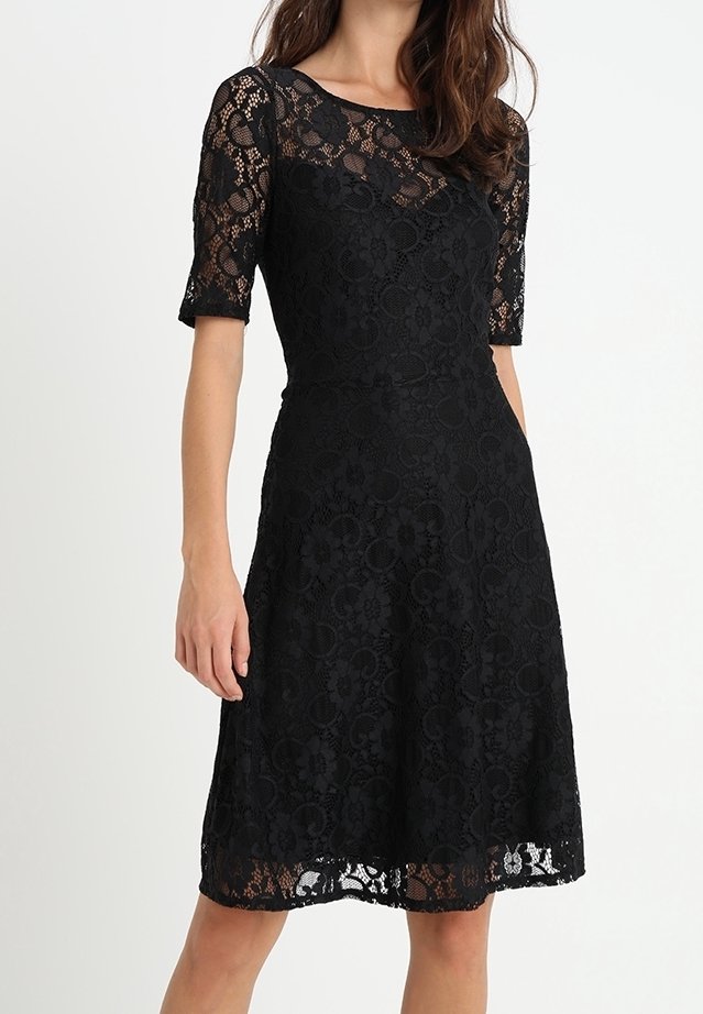 Robe en dentelle noire avec des manches courtes, un corsage ajusté et une jupe évasée. Le motif complexe de la dentelle comprend des détails floraux.