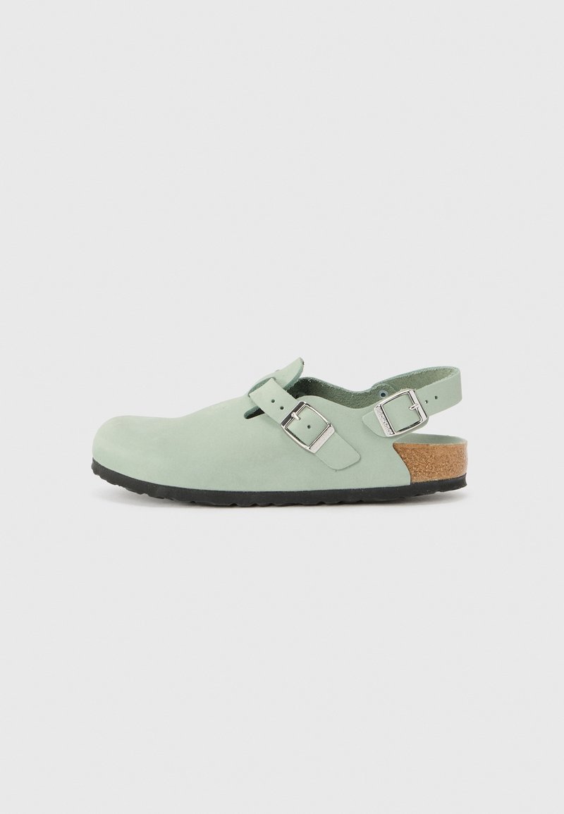 Sandale en cuir vert clair avec deux boucles argentées, talon ouvert avec semelle en liège et semelle en caoutchouc noire sur fond uni.