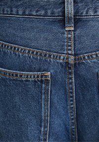 Jeans in denim di un blu scuro con due tasche posteriori, cuciture visibili in arancione a contrasto e una consistenza liscia.