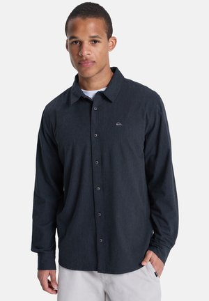 Dunkelblaues Hemd aus weichem Stoff mit Kragen, langen Ärmeln und kleinem Logo auf der linken Brust.