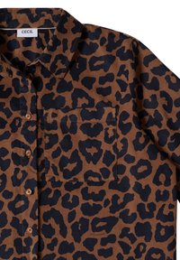 Chemise en velours côtelé marron avec motif léopard noir, poche avant, boutons et col, étiquetée "CECIL" à l’intérieur du col.