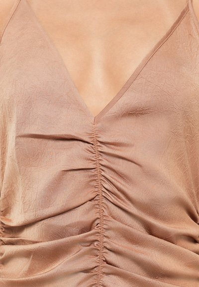 Dusty rose sleeveless top in lightweight, textured fabric. Features a deep V-neck and gathered detailing along the bust and sides.